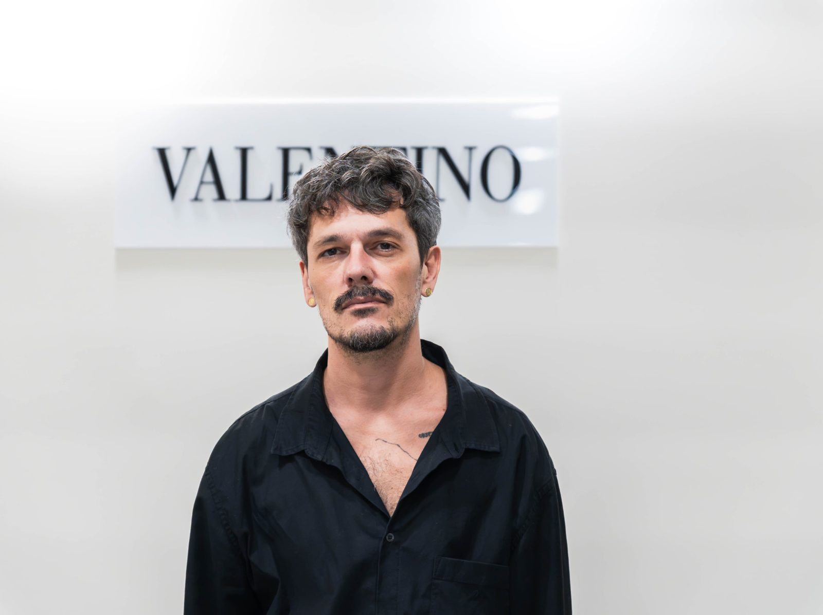 Convidado posando diante do painel Valentino