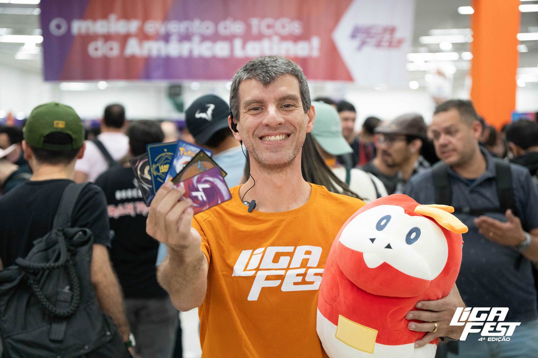 Participante sorrindo com cartas na mão e uma pelúcia vermelha