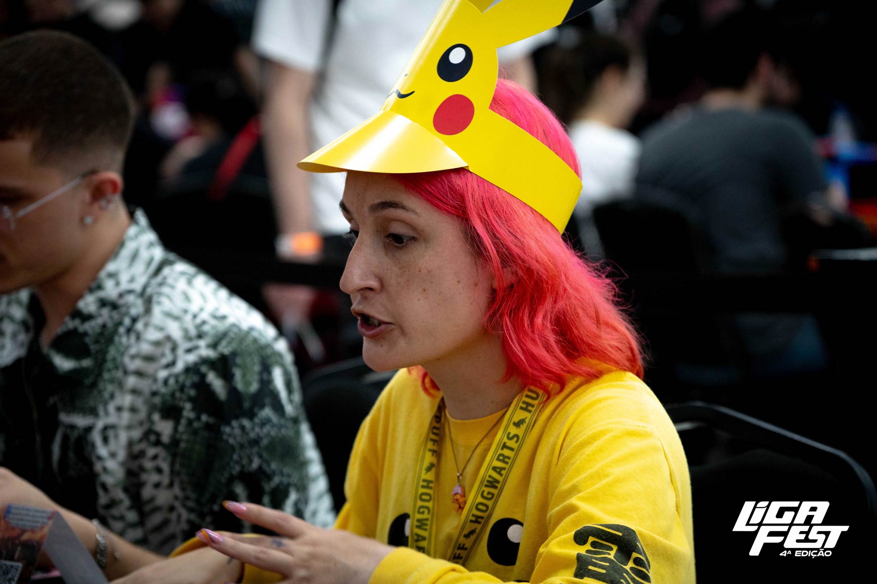 Participante de cabelo rosa com cosplay de chapéu de Pikachu durante o evento